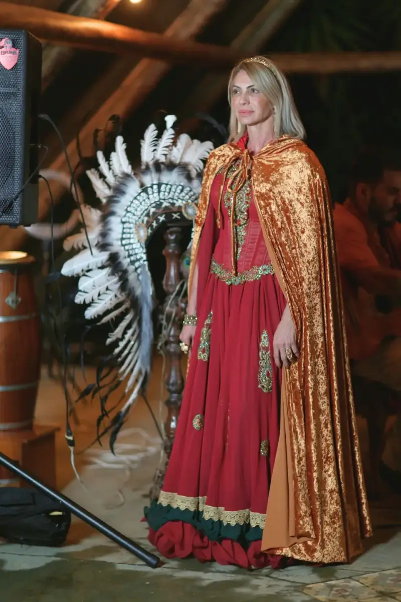 Valéria Tavares de vestido vermelho e capa dourada, no templo do Portal da Prosperidade