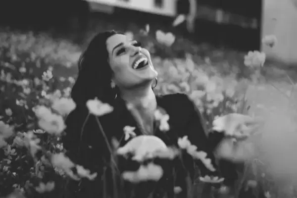 Mulher sorrindo em meio a um campo de flores